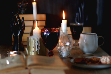 Books, lit candles, red wine, snacks and various deocration on the table. Dark academia or Halloween concept. Selective focus.