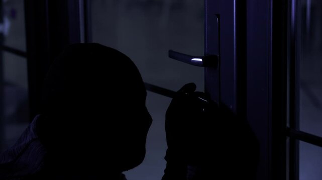 male thief in balaclava and gloves using master key to pick door lock to enter apartment at night, close up