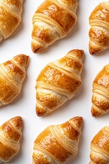 Golden brown croissants arranged on a white background creating a delicious pattern for breakfast