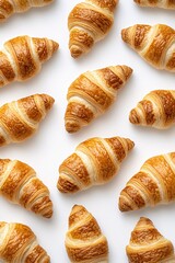 Golden brown croissants arranged on a white surface creating a pattern of delicious pastry