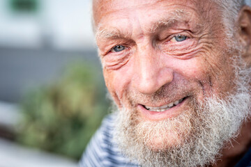 Portrait of an elderly man in retirement, enjoying peaceful moments outdoors, smiling contently, showing physical and mental wellbeing, wearing casual clothes, close-up with wrinkles, gray hair,