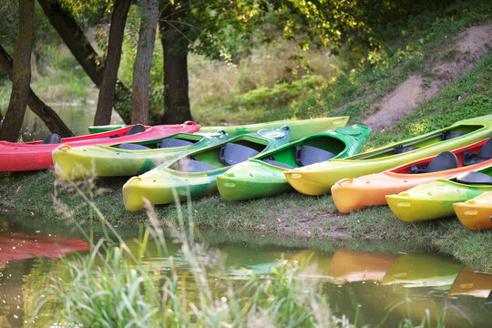 Many canoes of different colors on the river bank before training without people. Boating on the city river