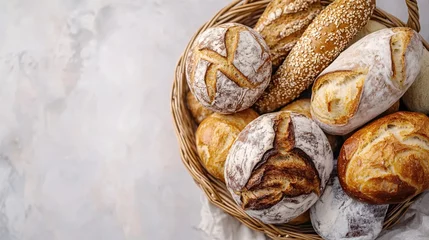 Fresh baked artisan bread in a wicker basket on a light marble background top view food photography