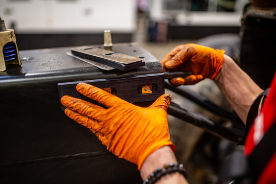 Mechanic working on engine parts greasing for construction mechanical equipment. Car industrial mechanic working with greasing elements with orange rubber gloves