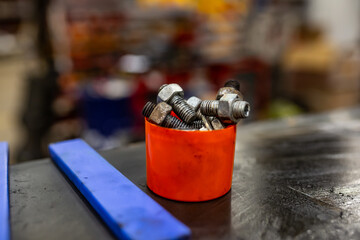 Car mechanic workshop orange bucket of oily screws