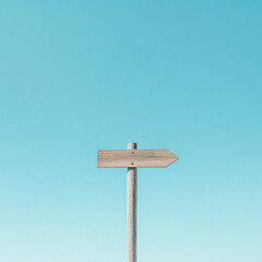 Wooden arrow sign with a clear blue sky in the background, representing direction or guidance, symbolizing choice, travel, or navigation in minimalist design.