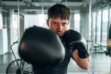 Black boxing gloves. Man is in the modern gym