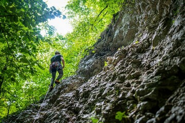 Obraz premium Man rock climbing up a steep mountain with copyspace.