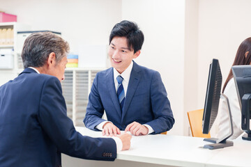 窓口で高齢者の来客の対応をする男性