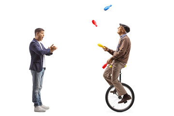 Amazed man clapping and watching an elderly man juggling on a mono cycle © Ljupco Smokovski