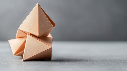 Three geometric paper shapes arranged on a textured surface with a gray background