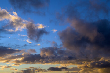 Blue sky with grey and orange clouds at sunrise horizontally © MiguelA