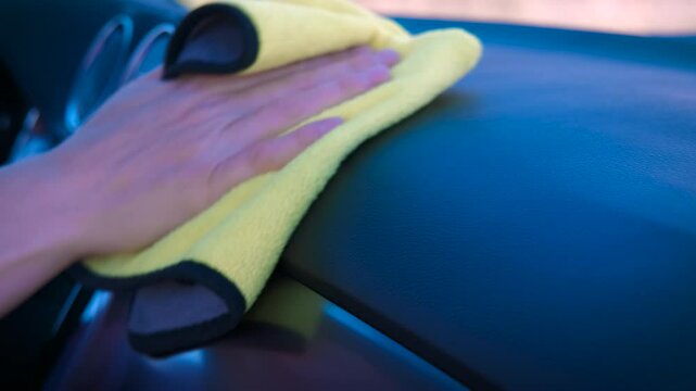 Woman cleaning salon of new auto. A female resting in car cabin and cleaning the dust from the dashboard.