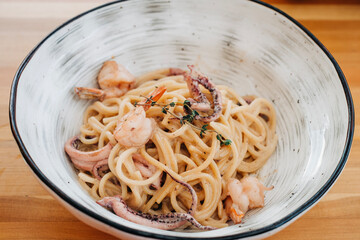Tasty pasta with seafood shrimps octopus calamari in the plate on the table