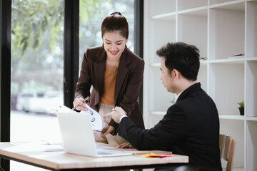 A team of business professionals work together in an office to analyze financial reports, sales strategies, and market statistics using laptops, documents, and graphs.