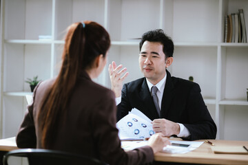A team of business professionals work together in an office to analyze financial reports, sales strategies, and market statistics using laptops, documents, and graphs.