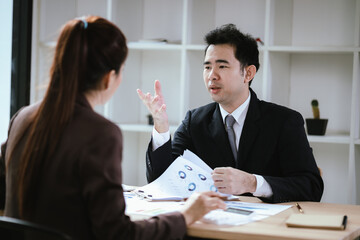 A team of business professionals work together in an office to analyze financial reports, sales strategies, and market statistics using laptops, documents, and graphs.