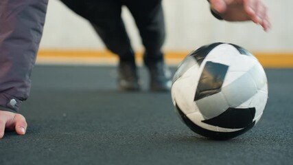 Close up of partial view of athlete performing push-ups alternating hand placement on soccer ball demonstrating strength outdoor urban ground