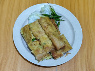 Egg martabak. Egg martabak is a traditional Indonesian food that tastes savory and delicious, served on a plate with pickles and chili.