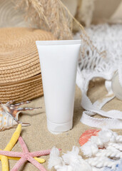 Sunscreen cream tube, sunglasses, towel, starfishes and seashells on a sand, cosmetic mockup