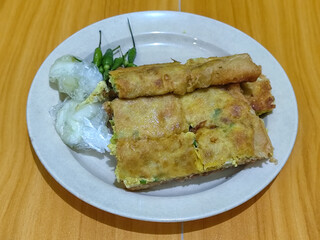 Egg martabak. Egg martabak is a traditional Indonesian food that tastes savory and delicious, served on a plate with pickles and chili.