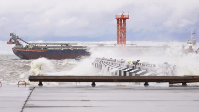 Red cargo ship moored near shore during light storm