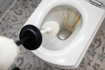 Сlose-up shot of a housewife in rubber gloves cleaning a toilet using a special cleaning product and a brush	