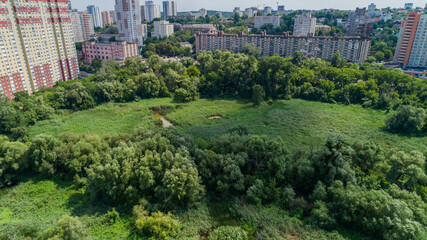Drone aerial view marshy lake in the metropolis, summer nature in sunny day, green trees