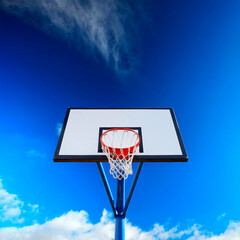 A vibrant basketball hoop stands tall against a bright blue sky, emphasizing a joyful atmosphere for outdoor play and sporting activities during the daytime