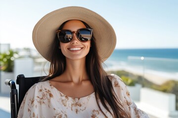 Fototapeta premium A stylish woman in a wheelchair enjoys a serene moment by the ocean, radiating confidence and joy while surrounded by a beautiful beach environment, showcasing freedom.