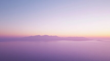 Fototapeta premium Tranquil sunset over a hazy island coastline. Soft pastel colors dominate the serene seascape. The silhouettes of structures and land are barely