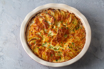 Potato gratin - graten (baked potatoes with cream and cheese) with rosemary and forks (Turkish name; Kremali patates)