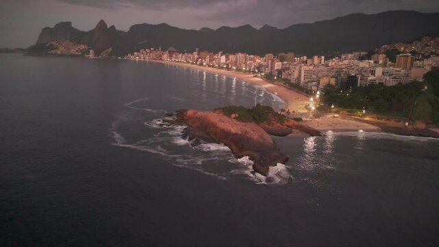 Sunrise in Arpoador Beach in Rio de Janeiro with orange sky and mountains at distance