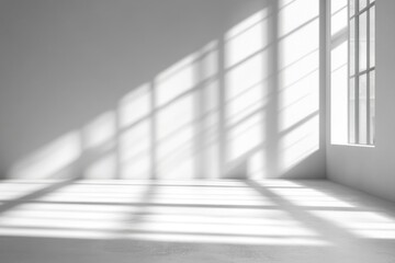 Fototapeta premium Sunlight streams through a large window into a minimalist white room, casting dramatic shadows on the floor and walls.