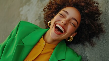 Fashionable young woman smiling joyfully in green attire with trendy hairstyle expressing genuine happiness while lying outdoors