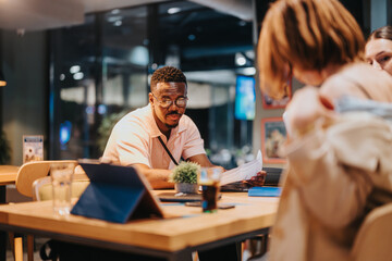 A diverse group of professionals engaged in a strategic brainstorming session during a late night meeting, focused on analyzing data and strategizing for business development.