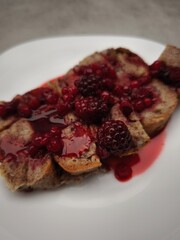 Slices of french toast topped with juicy blackberries and red currants, served on a white plate, creating a delightful  breakfast for valentines day