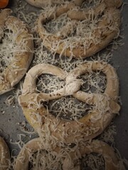 Freshly baked pretzels sprinkled with grated cheese and spices, resting on a baking sheet in a prague kitchen easy dinner