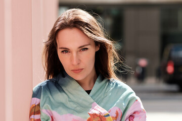Serious young woman leaning against pink wall in the city