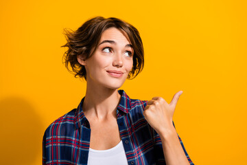Portrait of pleasant nice girl with bob hair wear plaid shirt look directing at offer empty space isolated on yellow color background