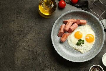 Tasty fried eggs and sausages served on grey table, flat lay. Space for text