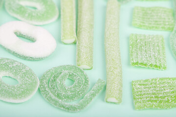 Assorted gummy candies on light green backdgroun. 