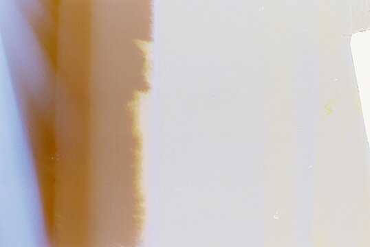 35mm film texture showcasing imperfections such as light leaks, color shifts, and film burn effects. This abstract composition highlights the raw and organic characteristics of analog photography
