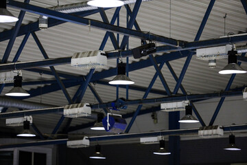 Ice hockey rink roof view with white ceilling lines, pipeline, LED ligting and music speakers hanging.