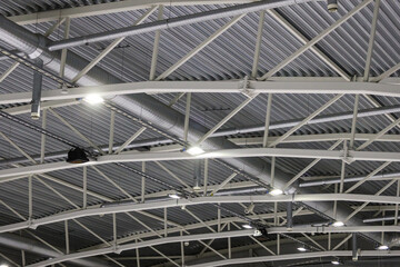 Ice hockey rink roof view with white ceilling lines, pipeline, LED ligting and music speakers hanging.