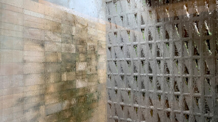 Obraz premium Blurred and dewy photo of lime stone tiles wall and roster breeze blocks. Taken behind dewed glass window with blurred and bokeh effect.