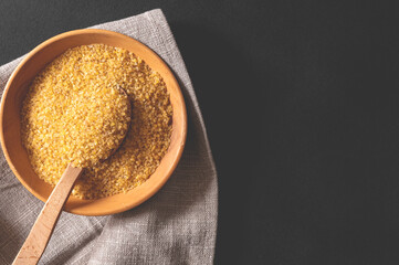 Wheat bulgur in a wooden plate on the table. Top view