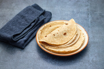 Roti is a soft, round flatbread made from whole wheat flour, commonly eaten in South Asian cuisine with various dishes.