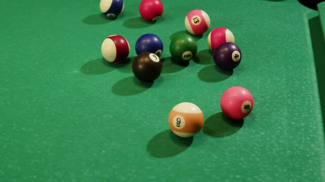 Young man playing American billiard pool poule close-up. Colorful balls on green billiards table .Billiard balls with numbers on a pool table. Billiards team sport.
