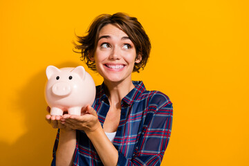 Photo of toothy beaming woman with bob hairdo dressed plaid shirt hold money box look empty space...